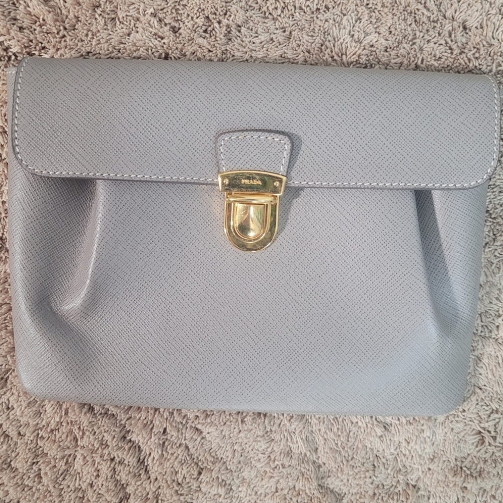 Prada handbag or clutch in gray Saffiano leather with gold-tone closure.